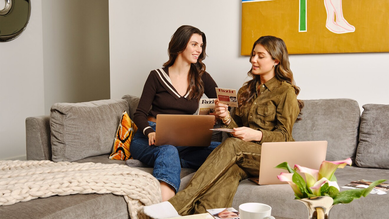 Two women relaxing on couch with laptops and Fazit products