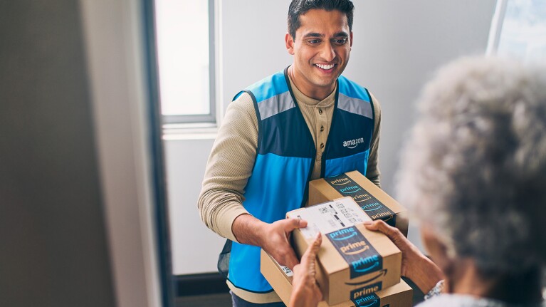 Amazon delivery person smiling while handing package to customer