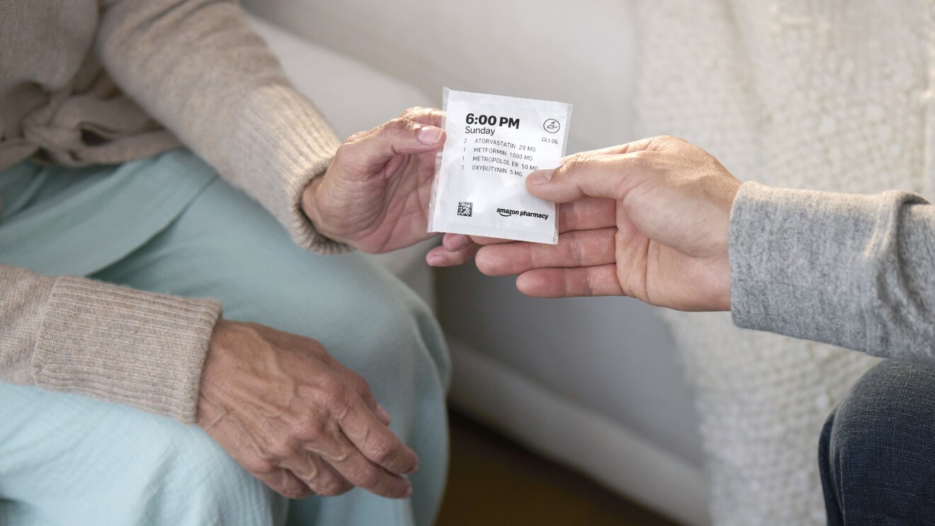 Hands exchanging Amazon Pharmacy medication package with time stamp