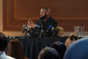 Lebron James checks phone during press conference with multiple microphones