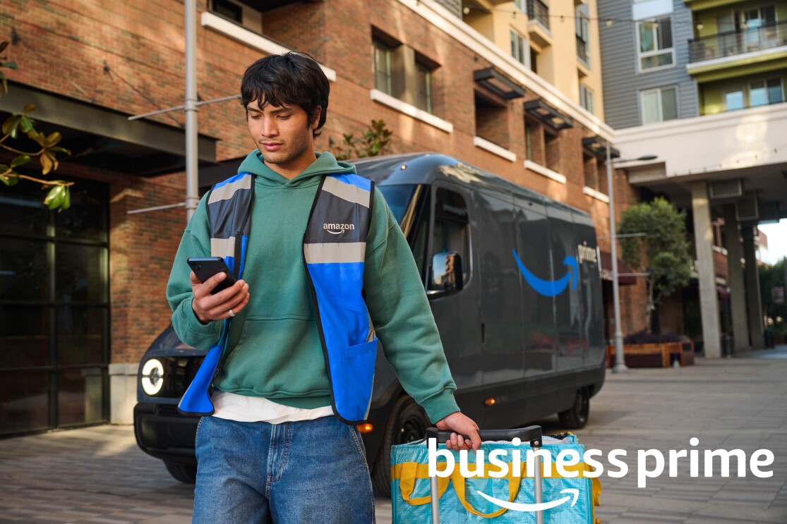 Delivery worker in Amazon vest holding smartphone and package