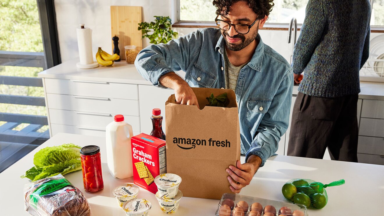 Man unpacking Amazon Fresh grocery delivery in bright kitchen