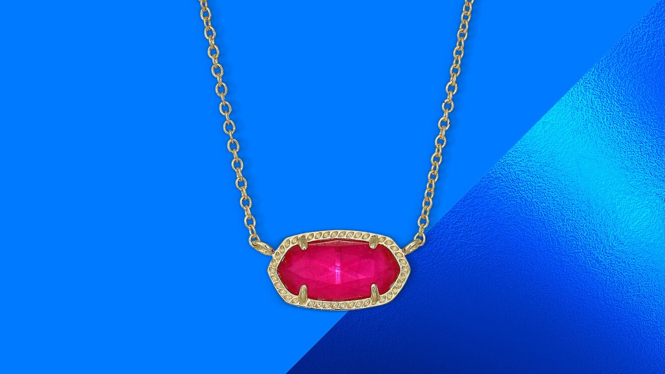 Gold necklace with oval pink gemstone pendant on blue background