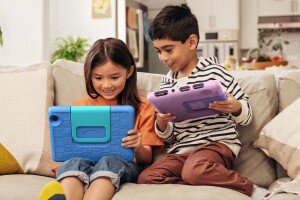 Kids relaxing with tablets on comfortable sofa