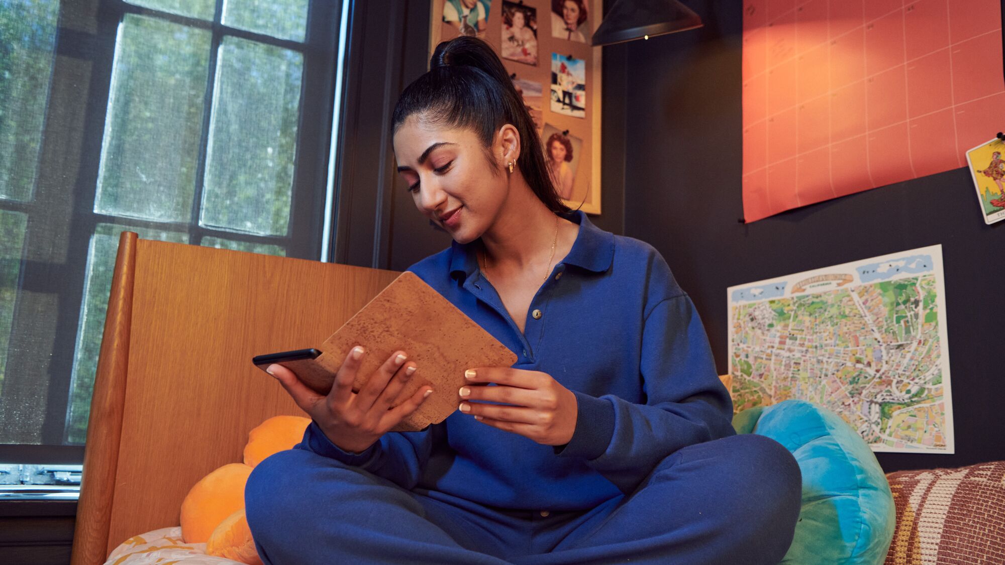 Woman holding Kindle in cozy room with map and photos on wall